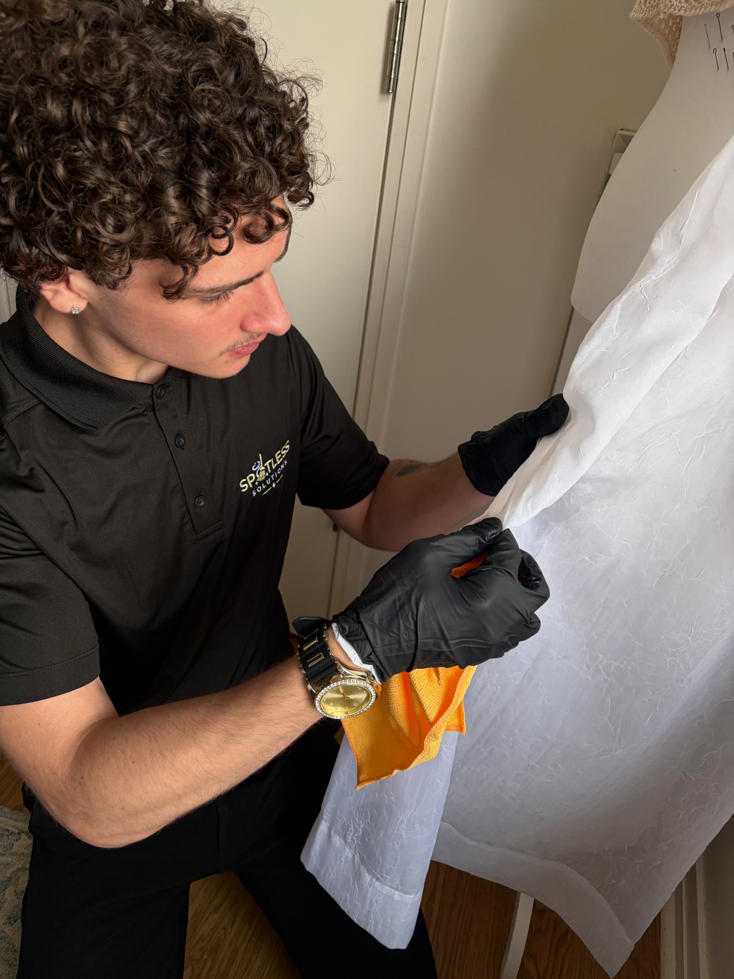 Spotless Solutions team member in branded polo hand-detailing a surface with a microfiber cloth
